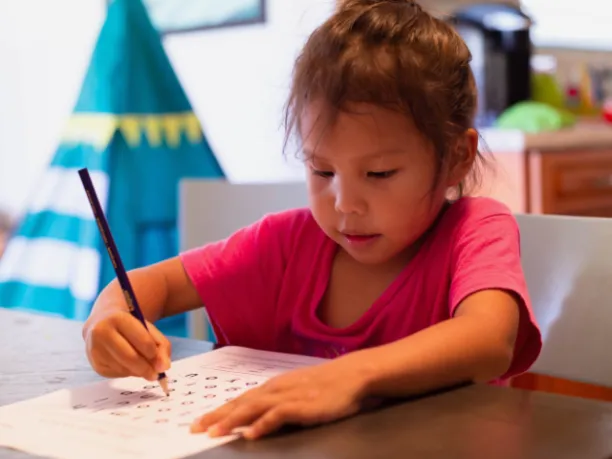 Young girl doing word find puzzle at a table indoors