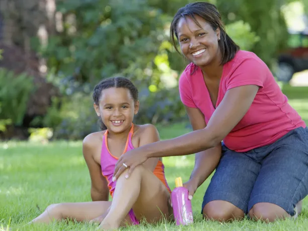 Mother applying sunblock to her daughter in the garden