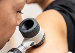 Photo of a doctor closely examining the skin on a patient's arm.