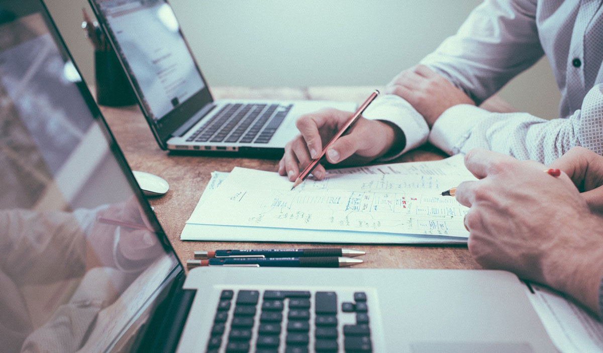 Image showing 2 sets of hands working on some laptop and documents