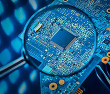 A photo of a magnifying glass highlighting a circuit board