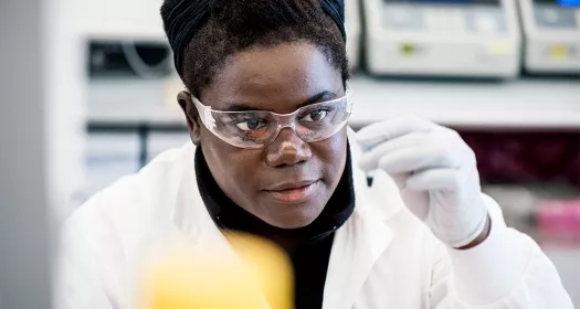 A female research scientist in a lab looking at a sample