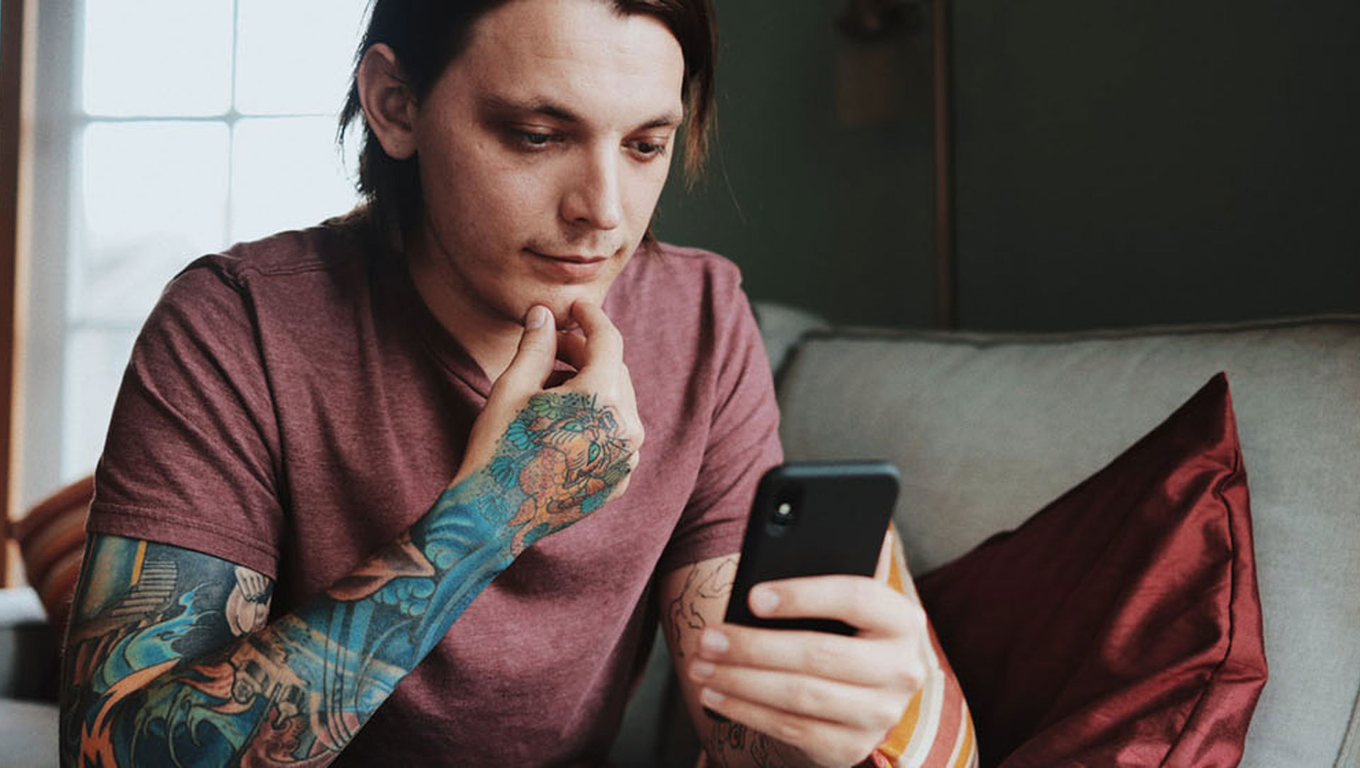 Man with sleeve tattoo looking at a mobile phone 