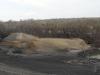 Area with dark soil and mounds of dirt with construction crew.