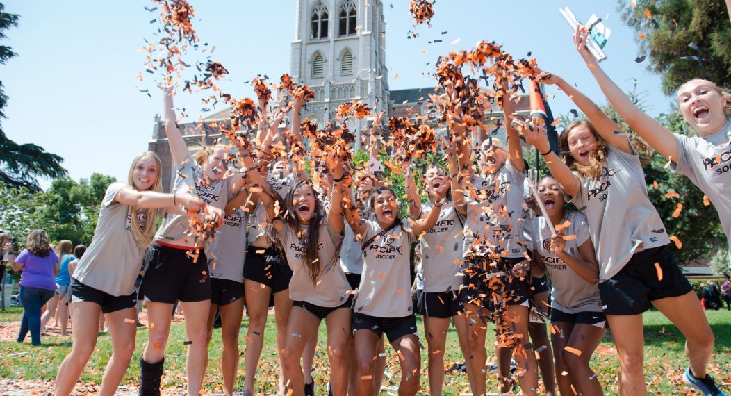 large group of students throwing confetti outside