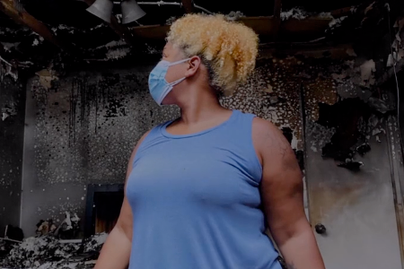 A woman stands in her damaged home after a fire