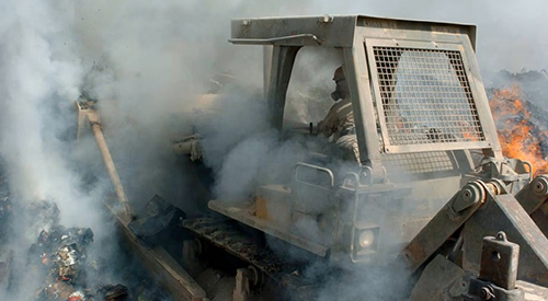 Logistics Support Area Anaconda, Balad, Iraqâ€•Sgt. Richard Ganske, 84th Combat Engineer Battalion, pushes waste materials deep into a burn pit. (Â©28th Public Affairs Detachment) 