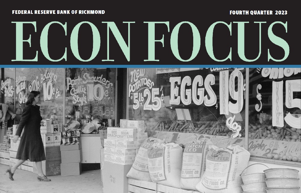 Black and white image of woman walking into store with prices on window. Econ Focus is written at the top as a header.