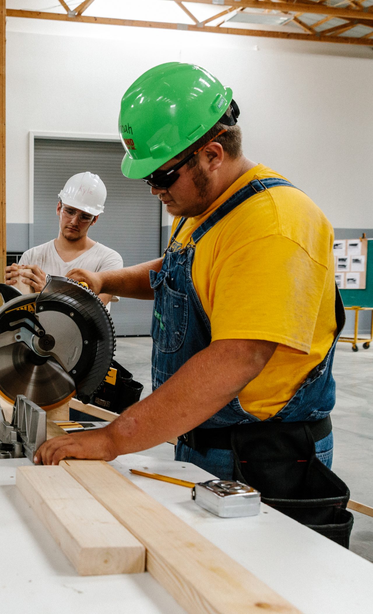 Two men cutting wood with a table saw. 