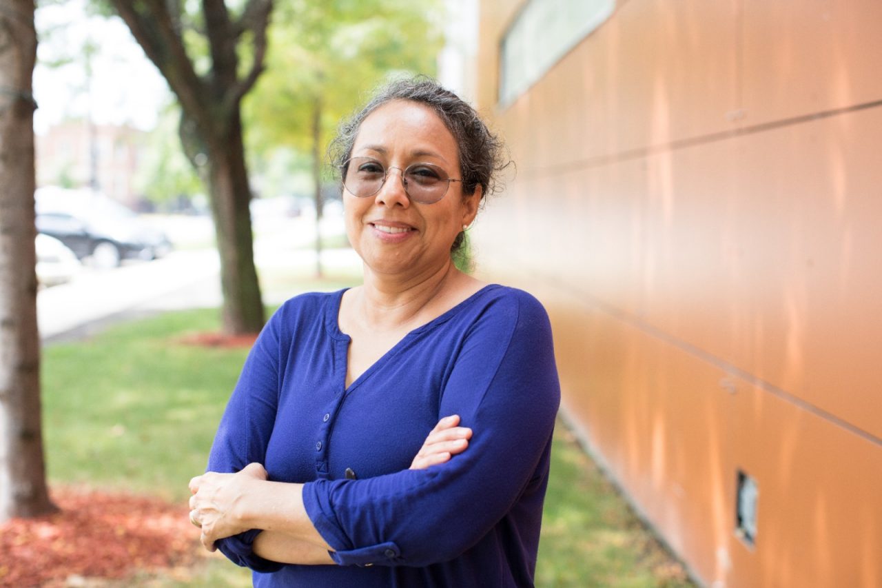 A woman poses in sunglasses outside of a building.