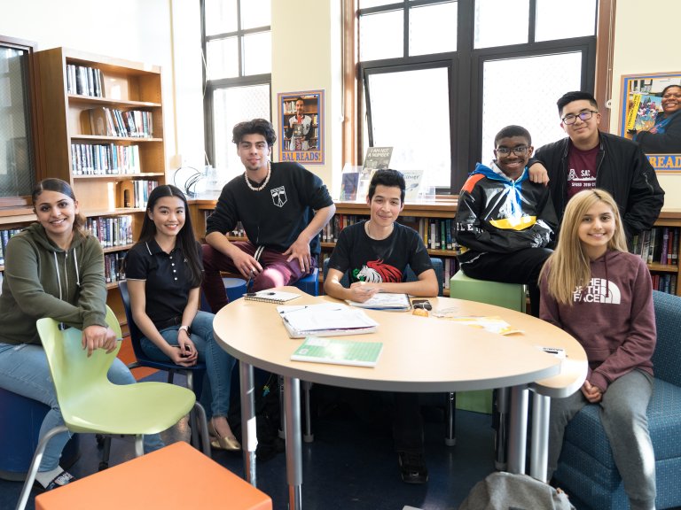 Group of students at desk smiling for the camera