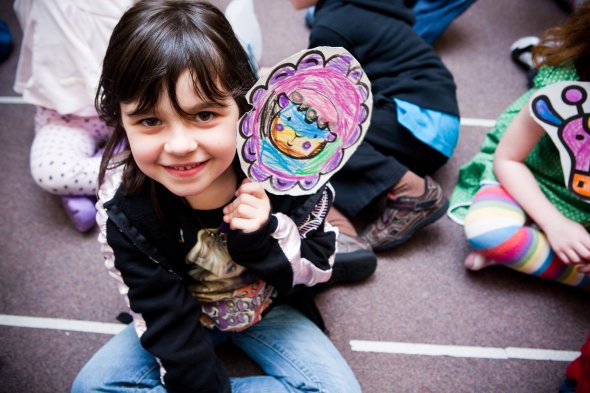 Student smiling holding a hand painted drawing