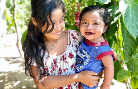 A smiling Lupe holds her joyful little brother José