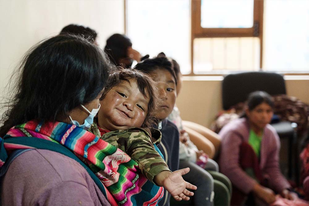 A baby smiles in the waiting room at Ayninakuna