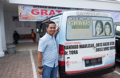 Smile Train social worker in front of branded vehicle 