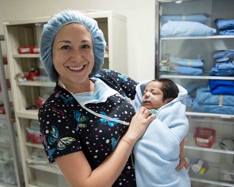 Doctor holds baby after cleft surgery