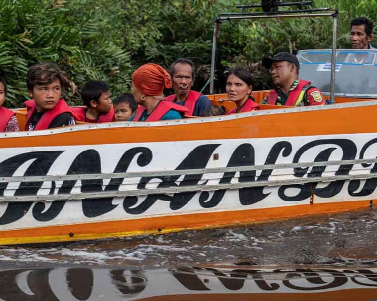 Alim and Rajib riding a boat with their family to the treatment center before cleft surgery