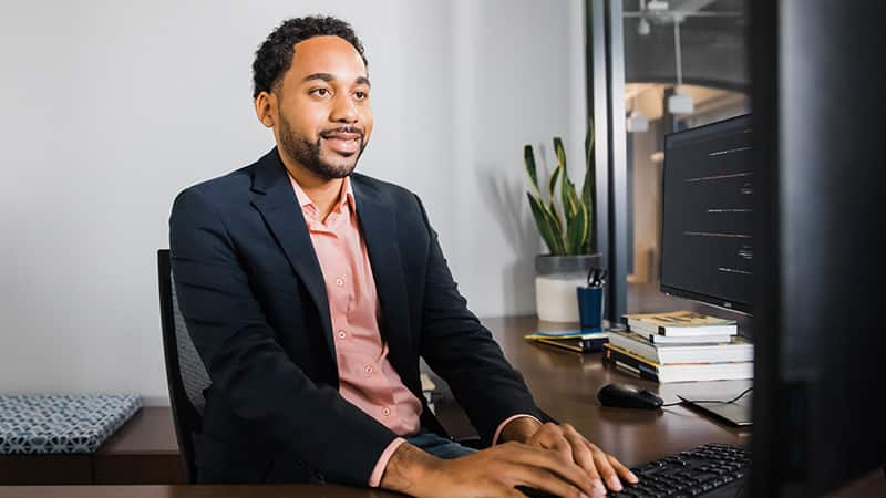 Gary Walker, an online master's in business administration alum, sitting in a suit jacket working from a computer desk.