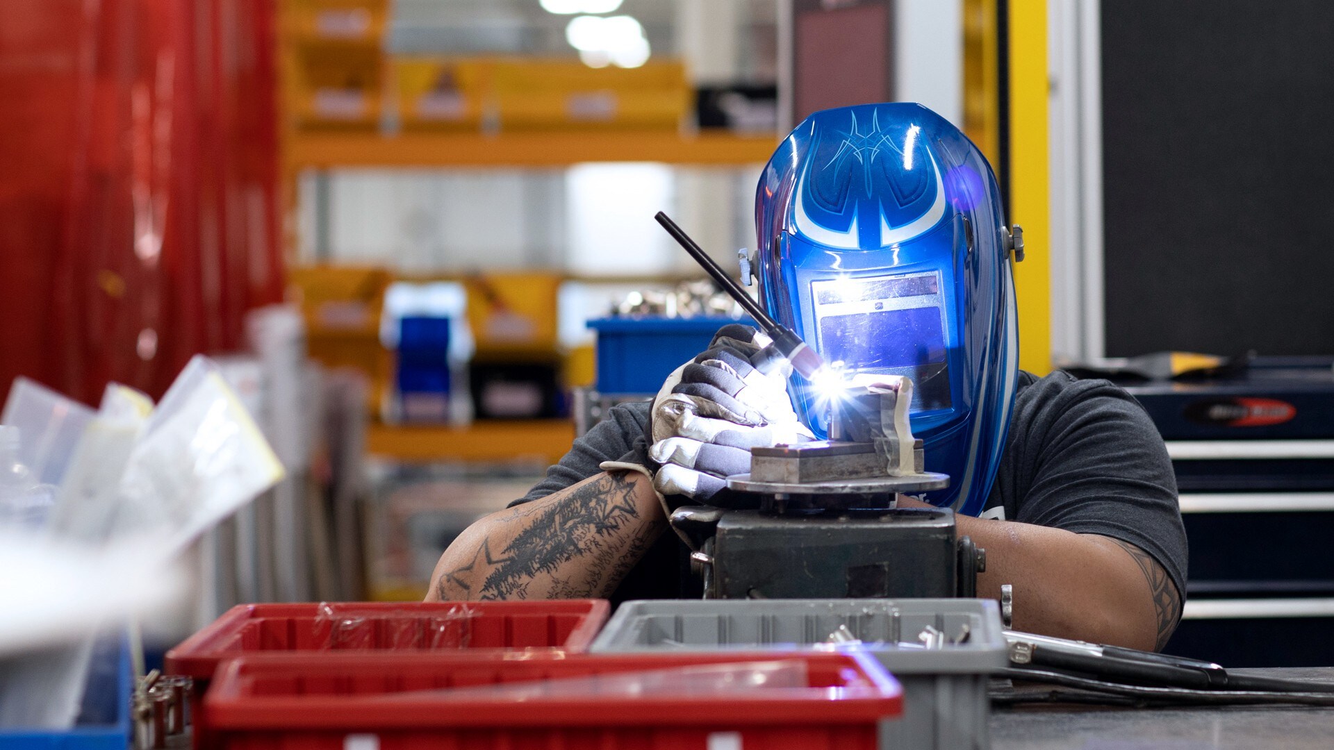 Industrial worker in manufacturing facility grinding piece of metal