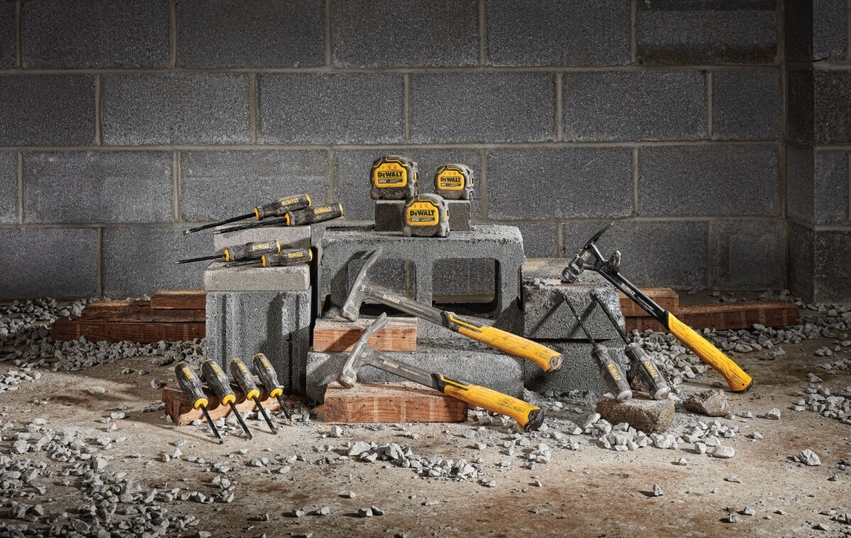 DEWALT TOUGHSERIES tape measures, hammers and screwdrivers on cinderblocks in front of brick wall with rocks