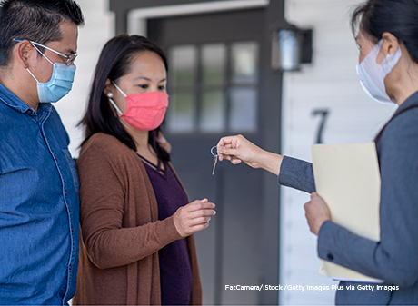 Man and woman with COVID masks on getting new home keys from their realtor