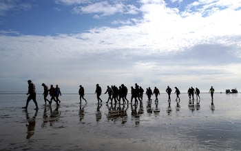 A group of people thought to be migrants walk up the beach after being brought in to Dungeness, Kent, onboard the RNLI Dungeness Lifeboat, May 17