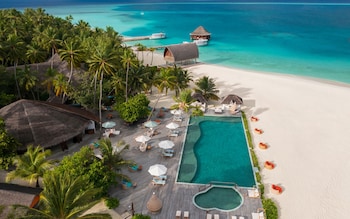 The main pool at Angsana Velavaru, Maldives. Surrounded by palm trees and white sand beach.