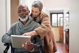 equity release interest rates & costs explained, couple look at tablet inside old fashioned house