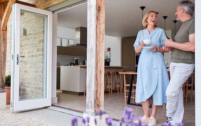 Happy couple stood on patio in summer time, discussing common equity release myths.