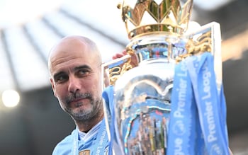 Pep Guardiola looks at the Premier League trophy