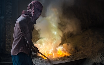 Workers remove a lead slag with a scoop, without any protective measures. Dust from lead is highly toxic