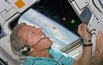 Loren Shriver, the commander of the space shuttle Atlantis, chases floating chocolate sweets on the flight deck in 1992