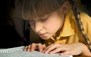 Blind 9 year old girl reading a braille book