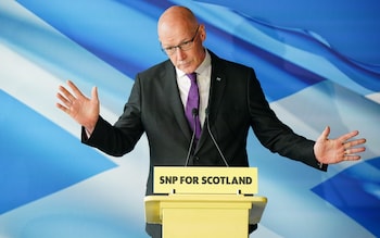 John Swinney gesticulates at a small podium