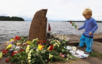 A young boy lays a flower opposite Utøya Island following the extremist attacks on July 25, 2011 