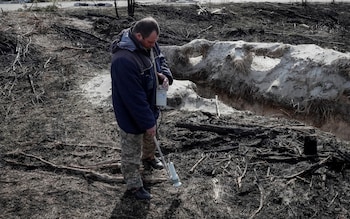 A dosimetrist measures the level of radiation around trenches dug by the Russian military in an area with high levels of radiation called the Red Forest