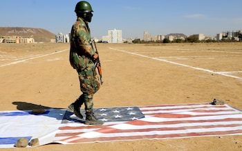 A Yemeni Houthi fighter walks on the flags of Israel and the US during a rally by the Iran-backed group held in Sanaa 