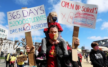 A parent protests with his young daughter on his shoulders and banners in each hand