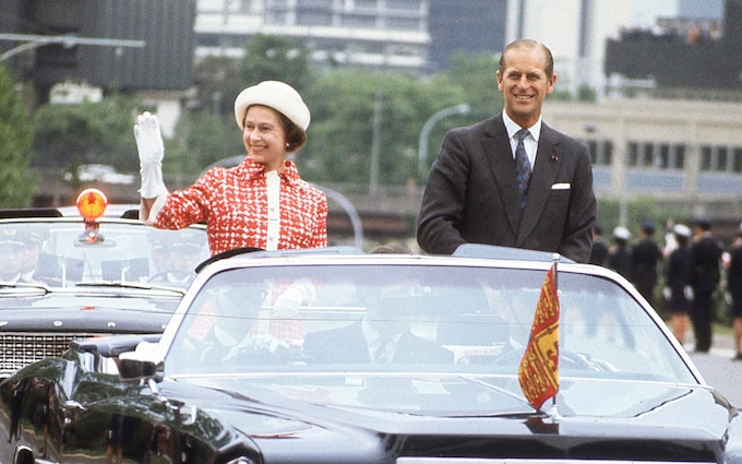 Queen Elizabeth and Prince Philip drive through Tokyo streets in open limousine during Royal Tour of Japan in May 1975 