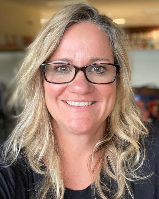 woman with long blonde hair and glasses smiling