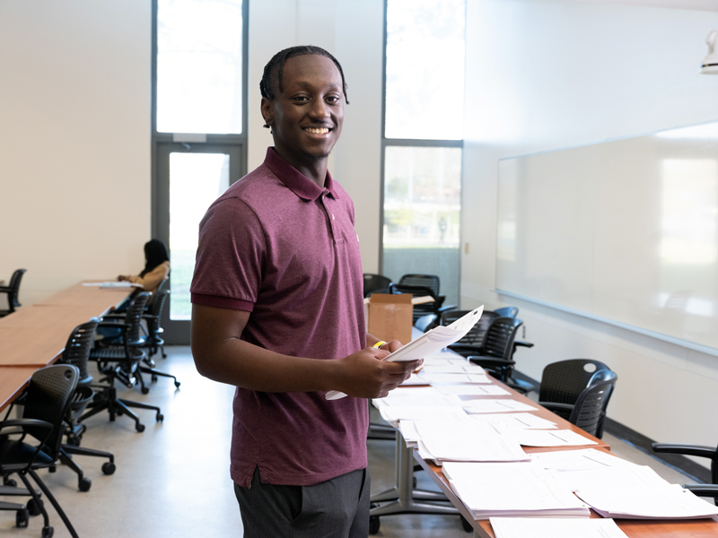 Nduati Macharia smiling, standing in a classroom