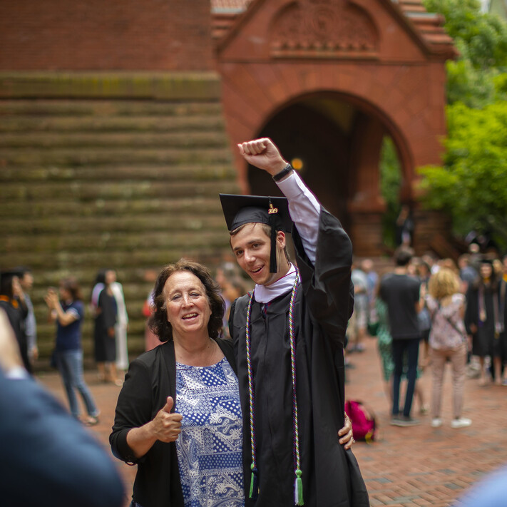 student at commencement with arms up