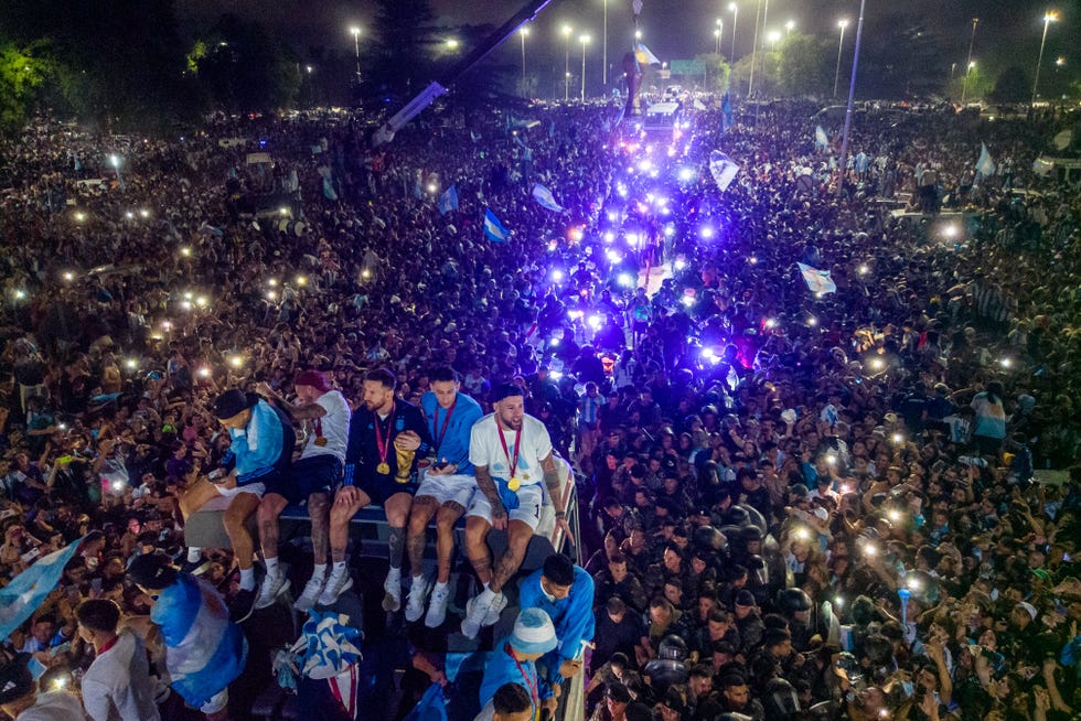 Argentina's captain and forward Lionel Messi (C) holds the FIFA World Cup Trophy on board a bus as he celebrates alongside teammates and supporters after winning the Qatar 2022 World Cup tournament in Ezeiza, Buenos Aires province, Argentina on December 20, 2022.