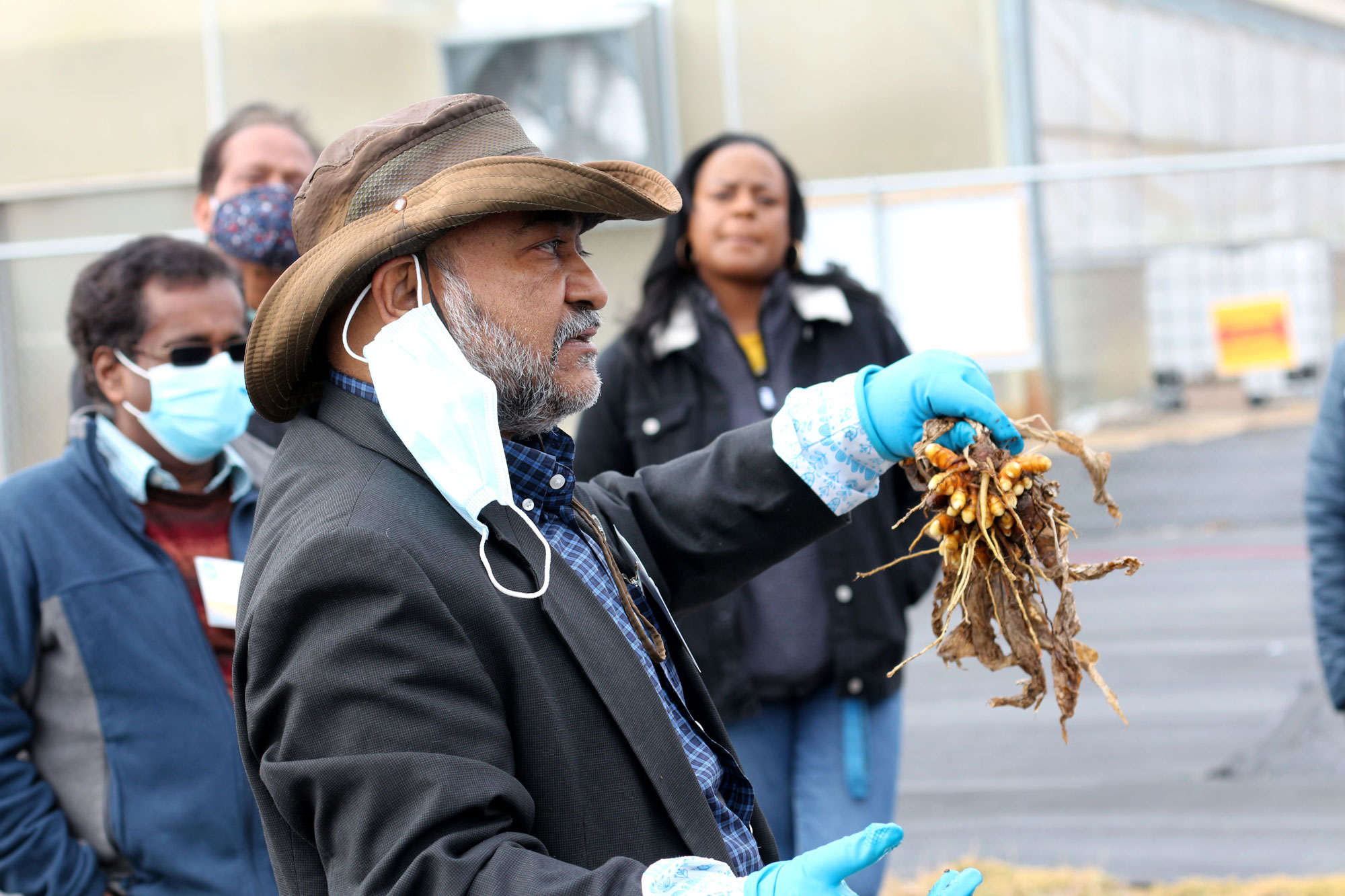 Two masked men, a woman and a man holding a root