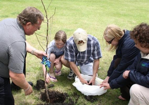 Valley City area office staff helped Cody Thibert and his daughter plant an apple tree they presented them in honor of Homeownership Month.  The Thibert’s newly finished deck can be seen in the background.