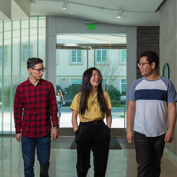 Three students walk side by side in hallway and discuss