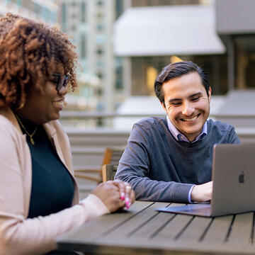 Two USF students working on a laptop, smiling