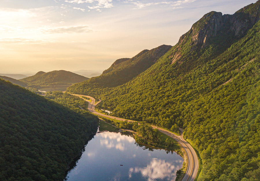 a road next to a mountain by a lake