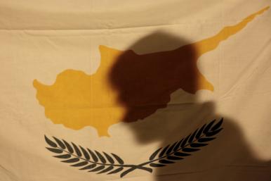 A protester's shadow falls across the flag of the Republic of Cyprus - source: Reuters