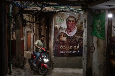 A man rides a scooter by a Hamas poster in a Palestinian refugee camp in Lebanon, May 18, 2024.